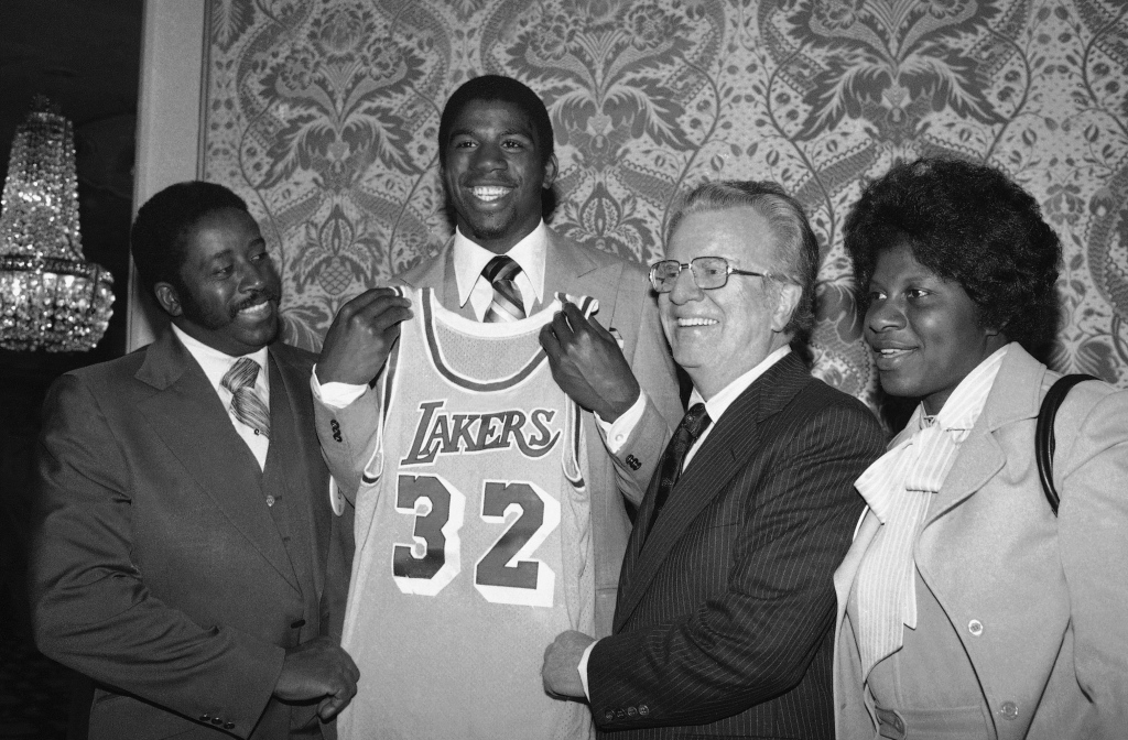 n "Magic" Johnson, second from left, beams as he holds a Los Angeles Lakers uniform at New York's Plaza Hotel, Monday, June 26, 1979 where he was selected by the Lakers in the first round of the National Basketball Association draft. "Magic" is joined by NBA Commissioner Larry O'Brien, second from right, and by his parents, Mr. and Mrs. Earvin Johnson, left and right, respectively. (AP