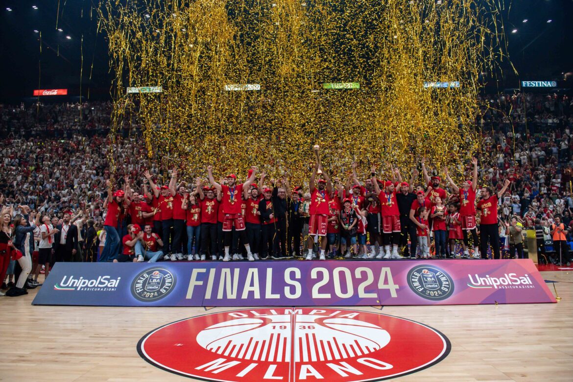 Kyle Hines alza il trofeo dello Scudetto vinto con l'Olimpia Milano.